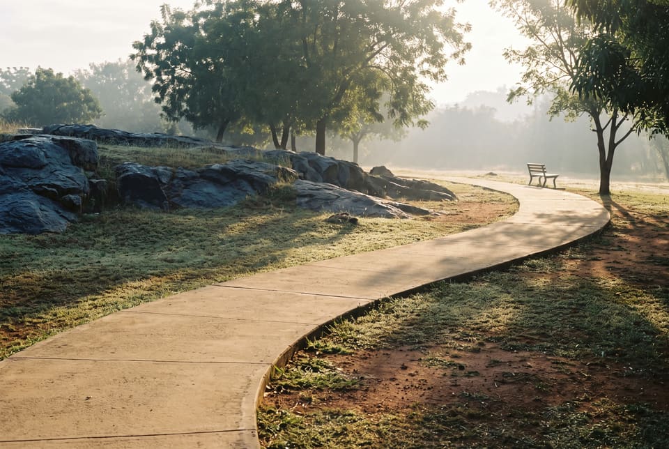 A paved path through Millennium Park in Abuja at first light, granite and grass either side