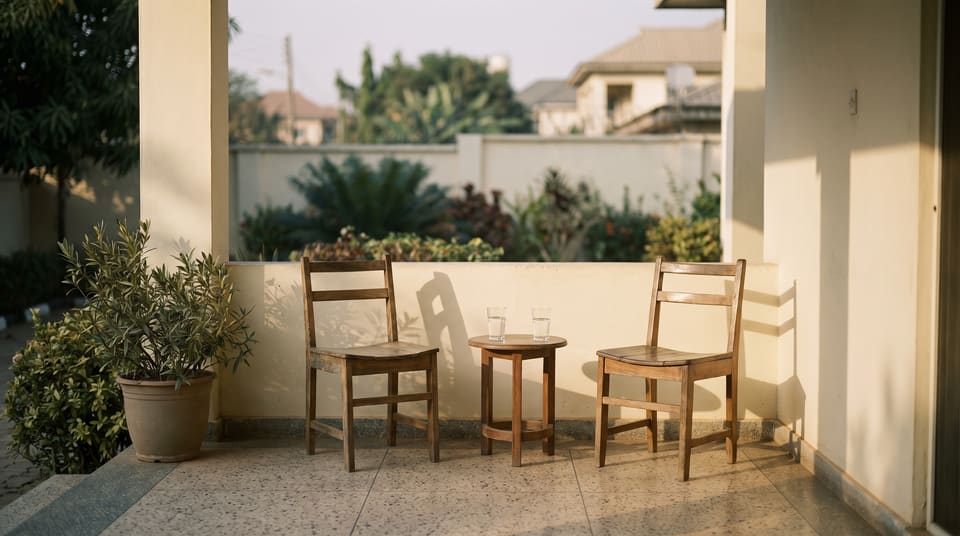 Two empty chairs on a compound veranda in late afternoon light